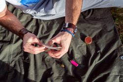 Man with rolling papers, tobacco and marijuana outside