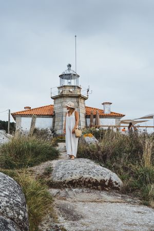 Woman in hat standing against beacon on seashore