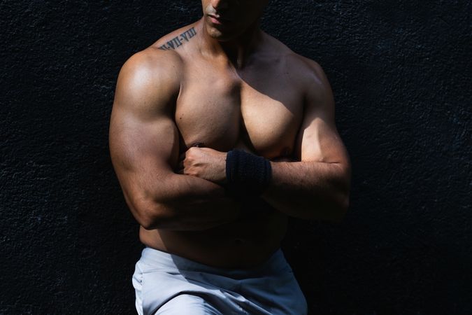 Anonymous positive shirtless Hispanic sportsman near wall