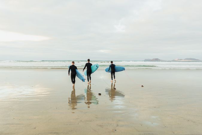 People with surfboard walking near sea