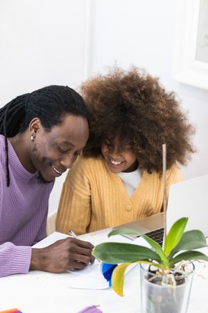 Black father helping daughter with homework on laptop