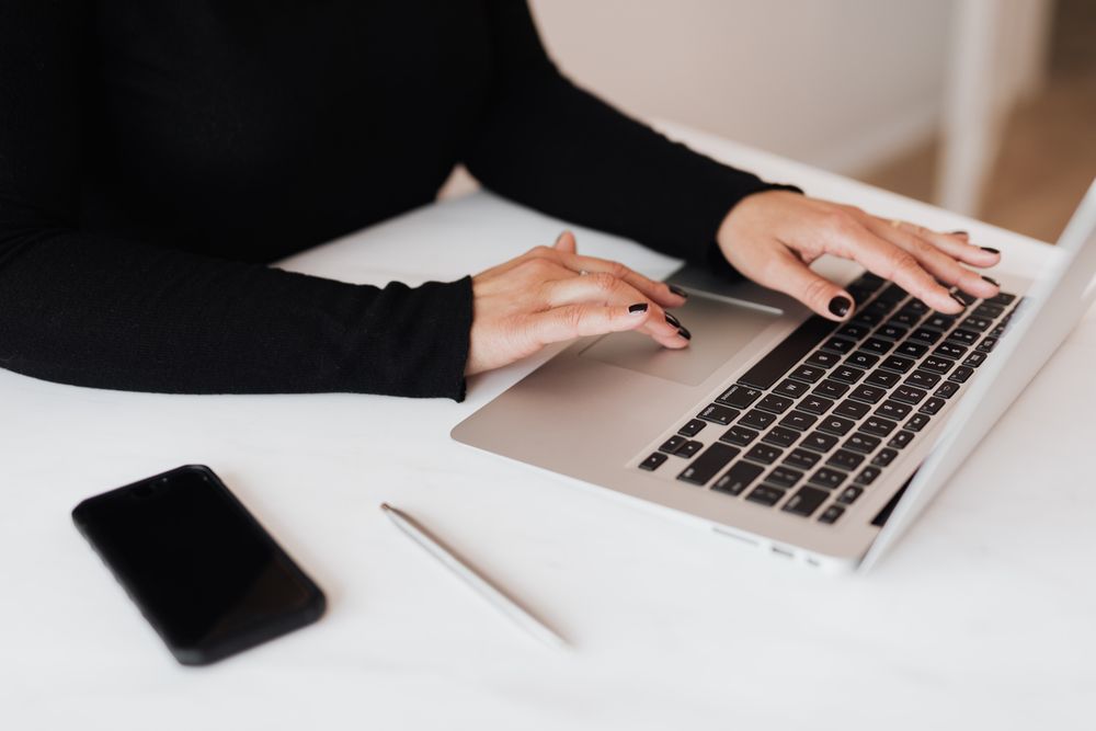 Cropped image of woman in dark image working on a laptop