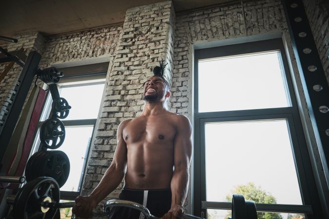 Black man exercising with barbell in gym