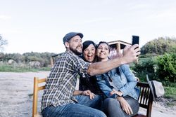 Three people sitting outdoors and taking a selfie