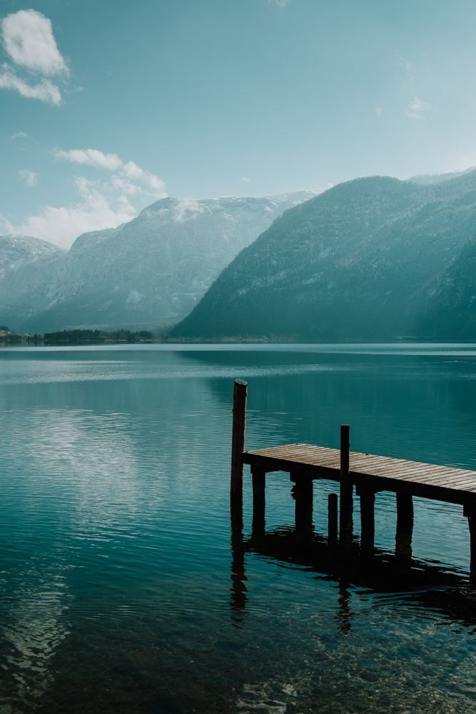 Lonely empty pier in turquoise water along mountain
