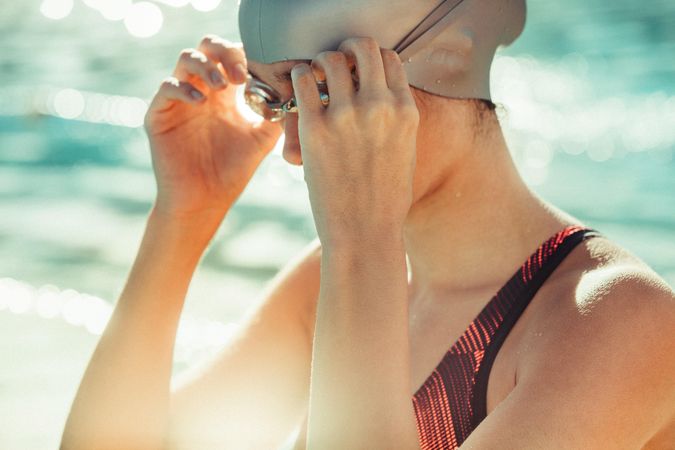 Woman in swimwear, swim cap and goggle near the pool