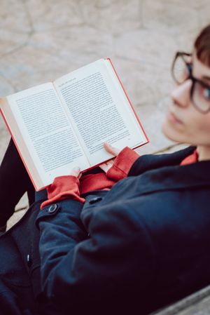 Young woman reading book on bench in park