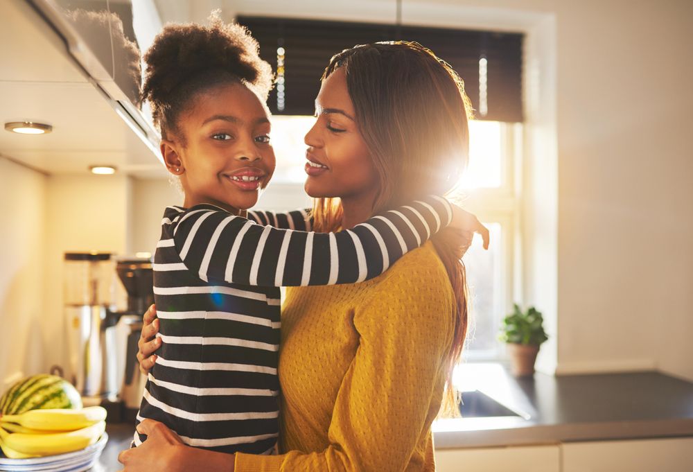 Happy mother and daughter hugging in bright kitchen