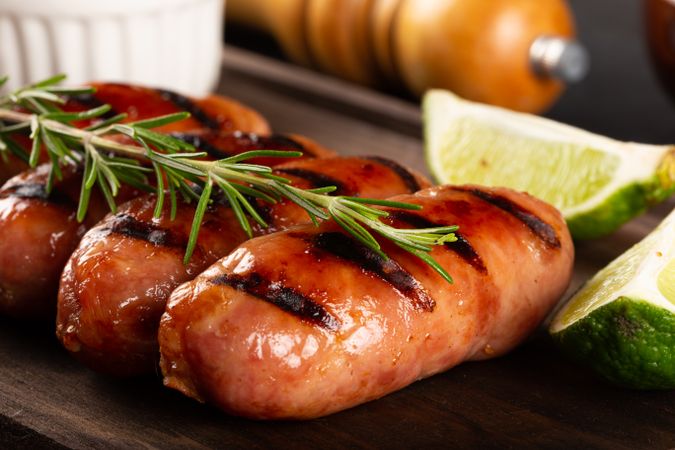 Close up of grilled sausages on board with lime slices