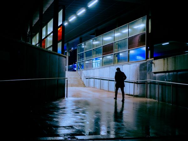 Silhouette of man walking on sidewalk during nighttime