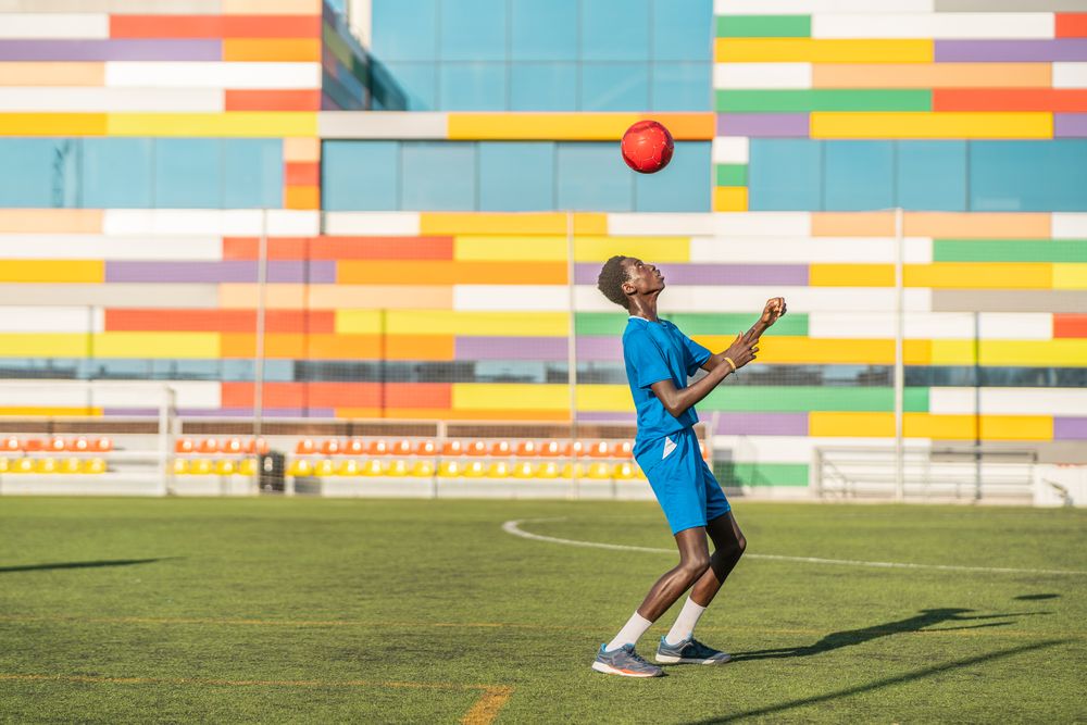 Black teenager jugging football ball on head
