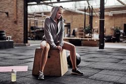 Woman sitting on box in gym with medicine ball