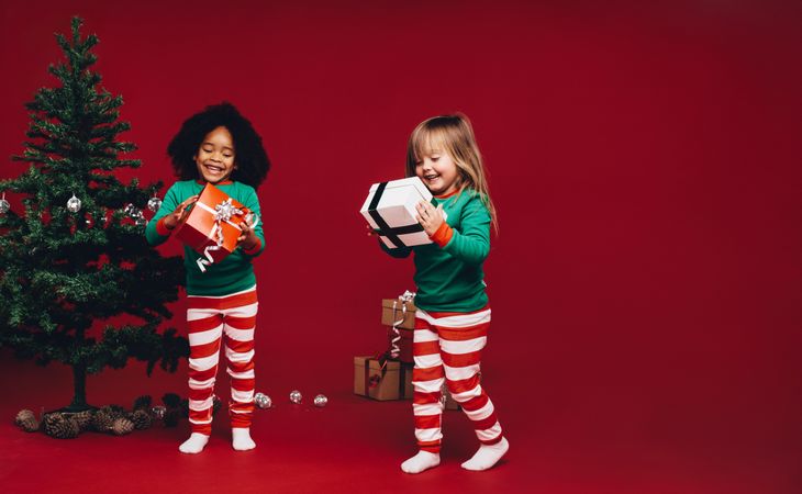 Happy little kids holding wrapped Christmas gifts