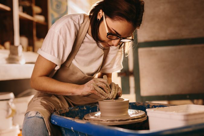 Female potter concentrating on making a clay bowl