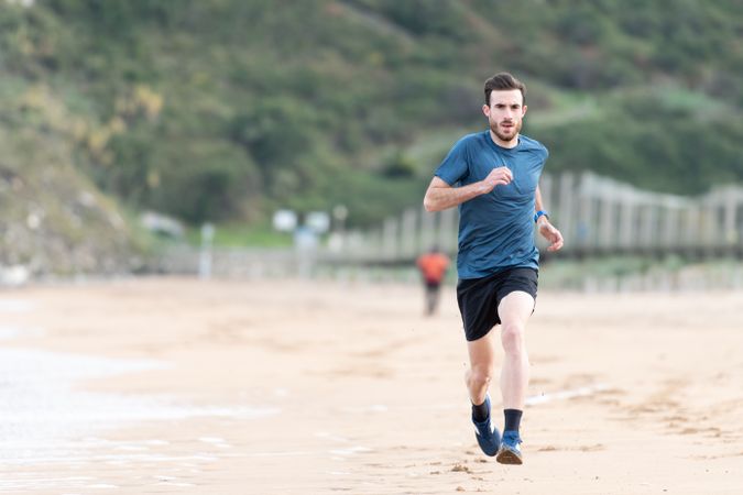 Sportsman in active wear jogging on lonely beach