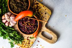 Looking down at pot of traditional Georgian sauce Adjika with garlic bulb & raw ingredient with copy space