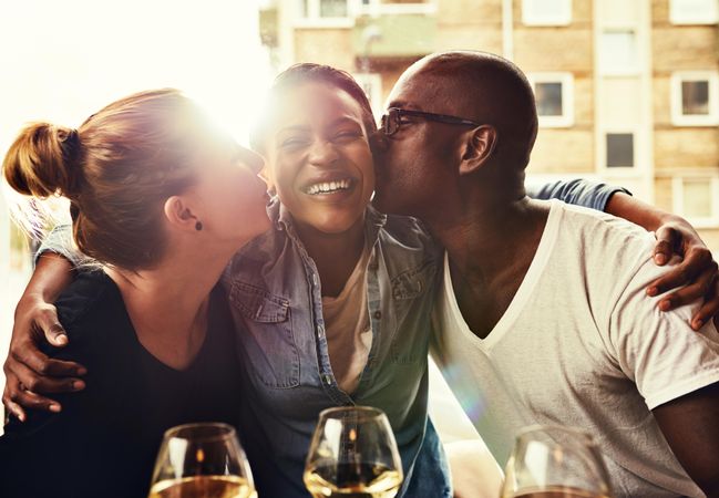 Woman being kissed on the cheek by a man and woman