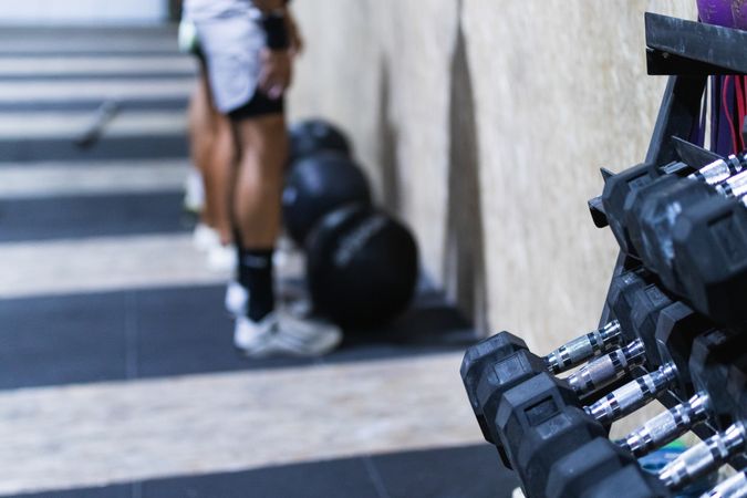 Athletes standing near fit ball and rack of dumbbells