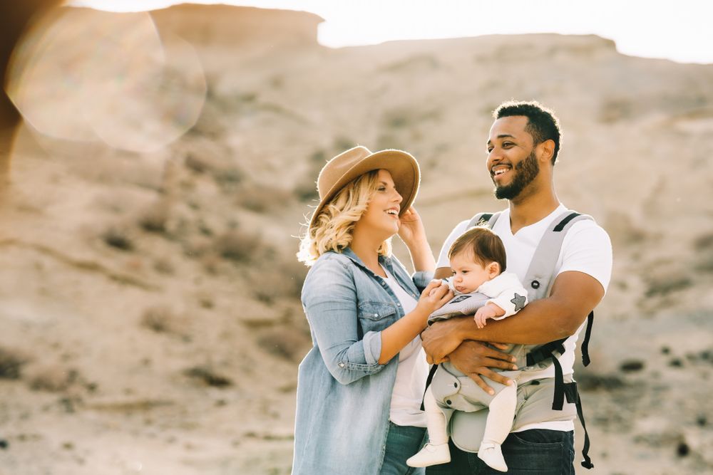 Diverse parents dancing while standing with baby