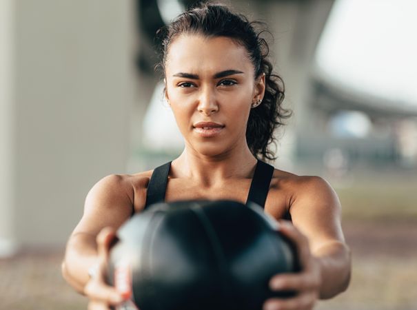 Healthy woman holding out a medicine exercise bar with her arms