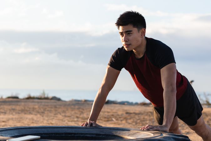 Athletic man doing push ups against tire