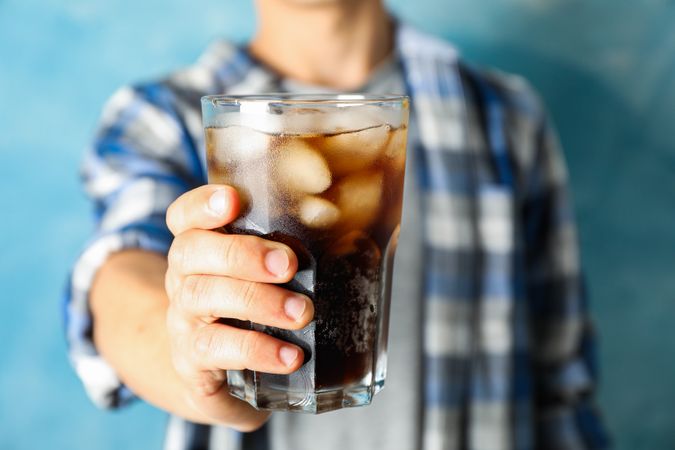 Male hand holding a glass with cola, close up