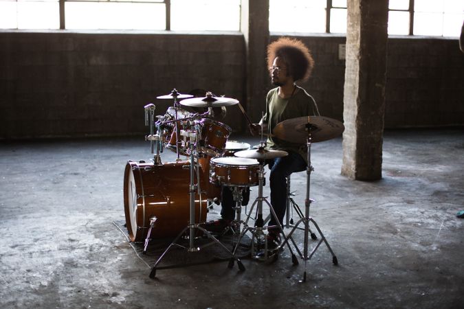 Side view of man playing drums in spacious garage