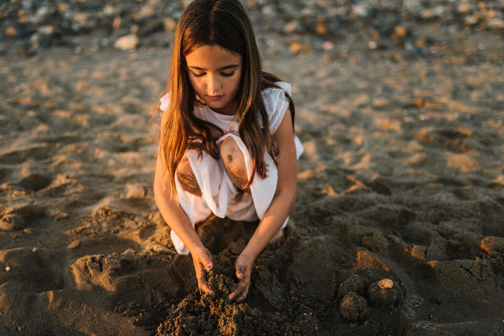 Adorable girl playing with sand on beach