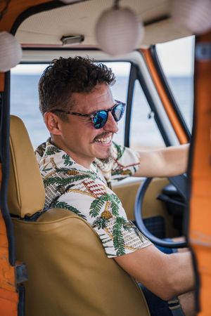 Cheerful man in sunglasses riding car and smiling at camera