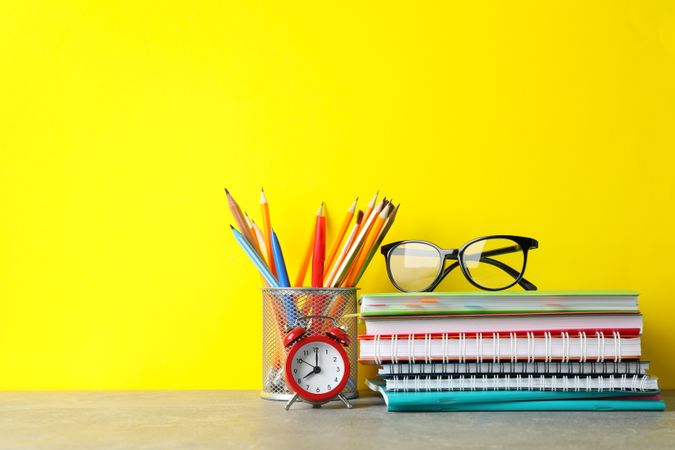 Colorful stationary on grey table against yellow wall with copy space