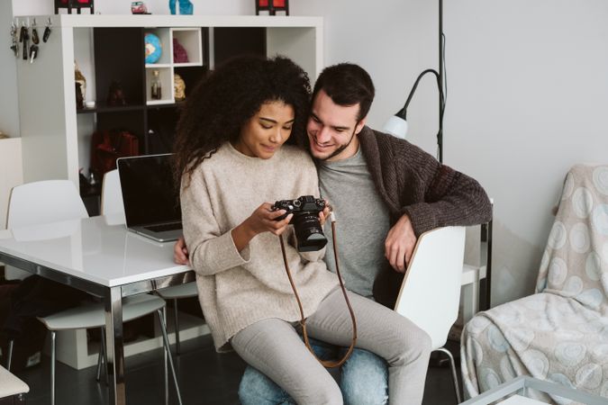 Multiracial couple looking at photo camera at home