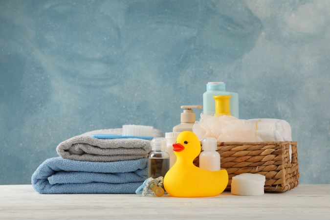 Baby hygiene accessories on wooden table against blue background