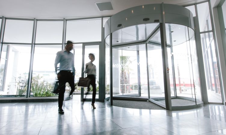Motion blurred shot of two business people talking through modern office hallway