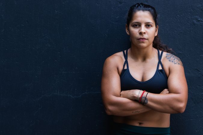 Hispanic sportswoman standing near wall
