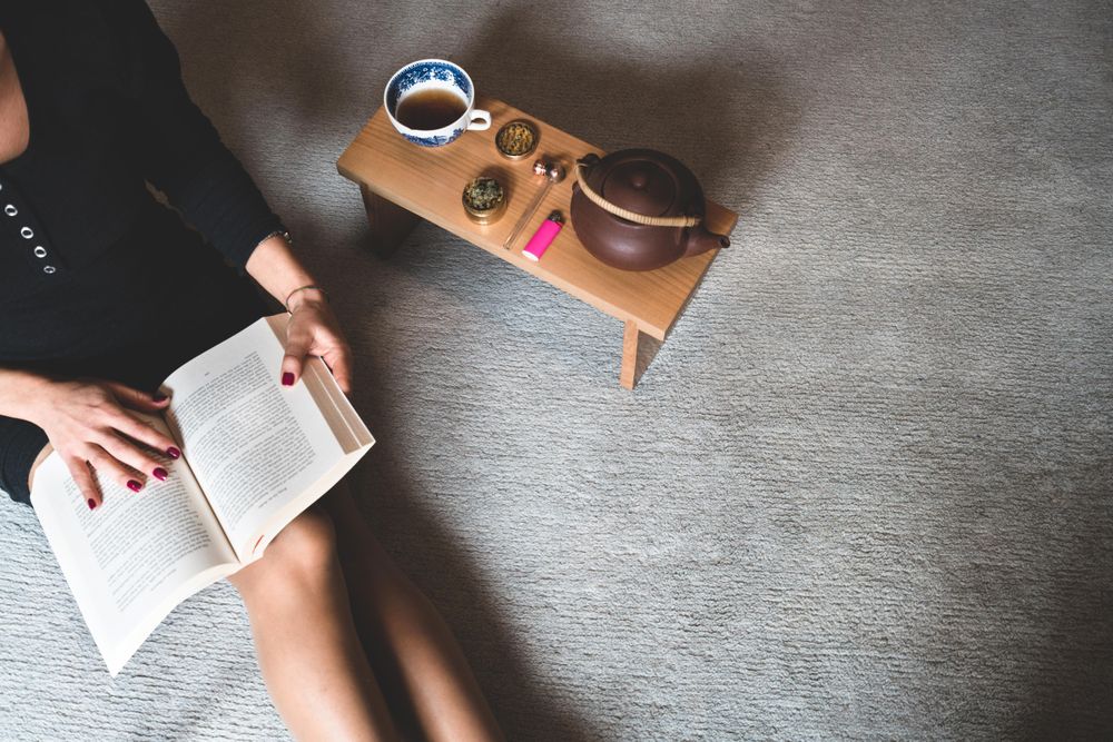 Woman with book and trey of marijuana paraphernalia and tea