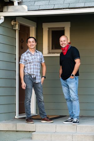 Two men standing in front of front door to house smiling and looking at camera