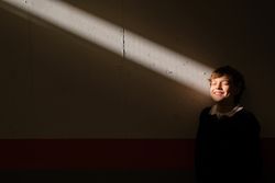 Smiling boy standing with closed eyes at wall in sunbeam