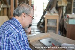 Asian carpenter on phone in workshop 5pggaN