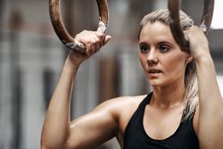 Focused woman holding onto gymnastic rings before workout