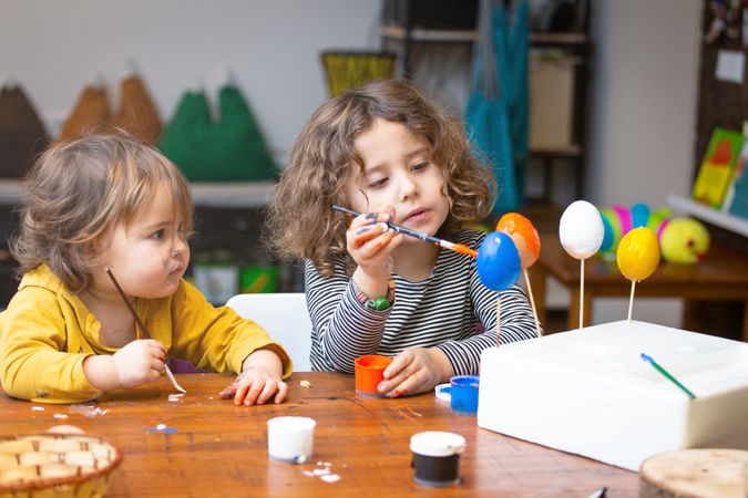 Sisters painting Easter eggs at home