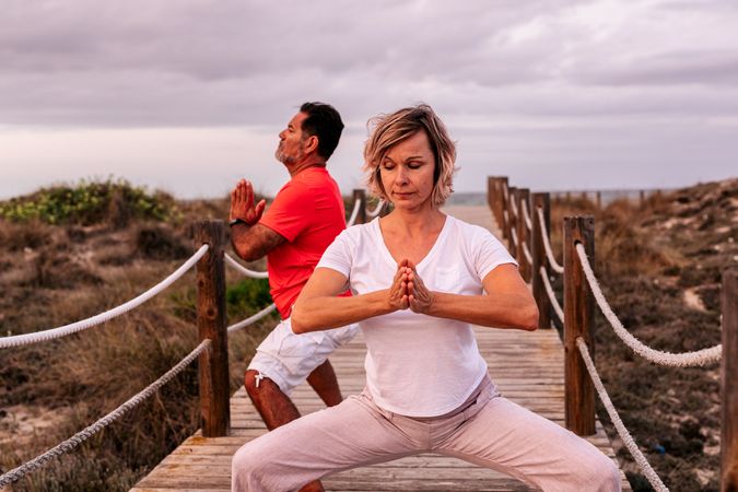 Adult couple meditating on wooden path