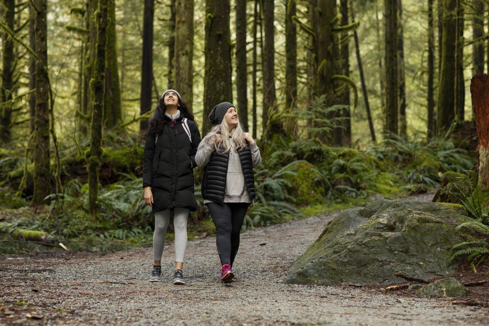 Young female and woman walking on a trail smiling while looking up