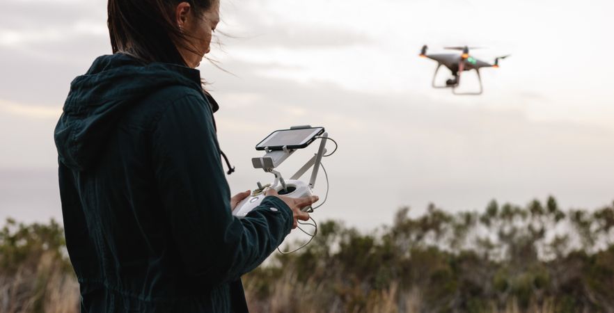 Woman navigating a flying drone with remote control