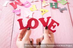 Hands holding paper letters that form the word love bYMA6b
