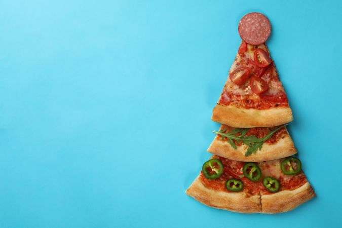 Christmas tree made of pizza slices on blue background