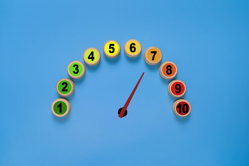 risk level meter indicator from low to high with 1 to 10 scale numbers on wooden blocks. isolated on blue background. concept of risk management