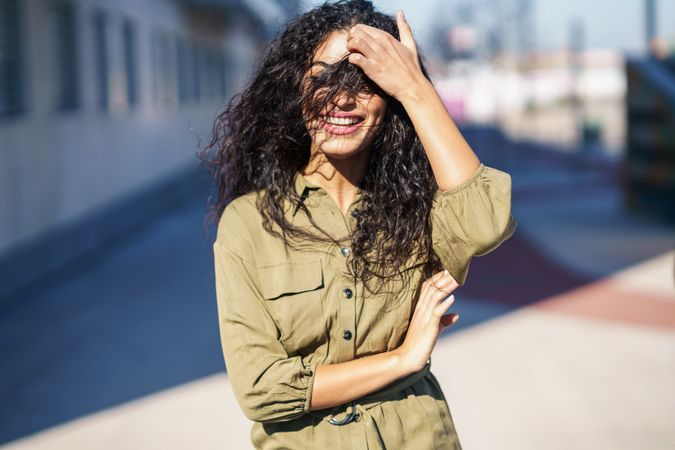 Smiling Middle Eastern woman standing outside with hair in her face
