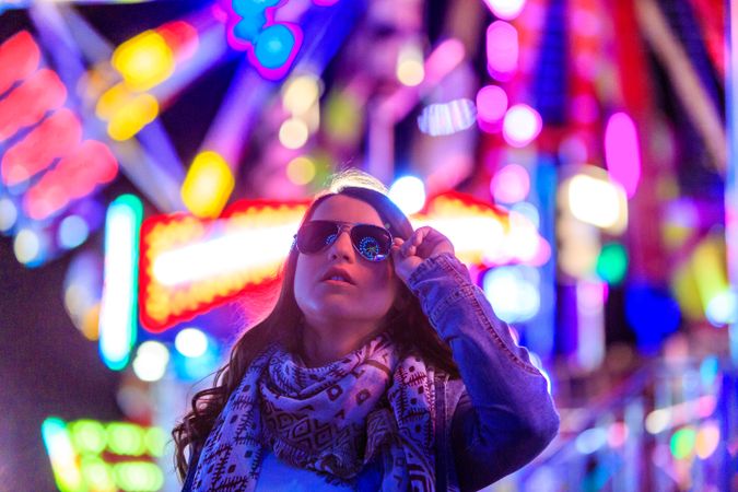 Stylish young woman near illumination on street