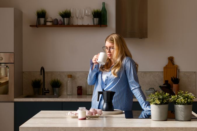 Woman sipping coffee in sunlight kitchen