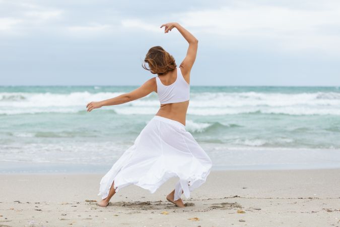 Anonymous woman dancing near sea